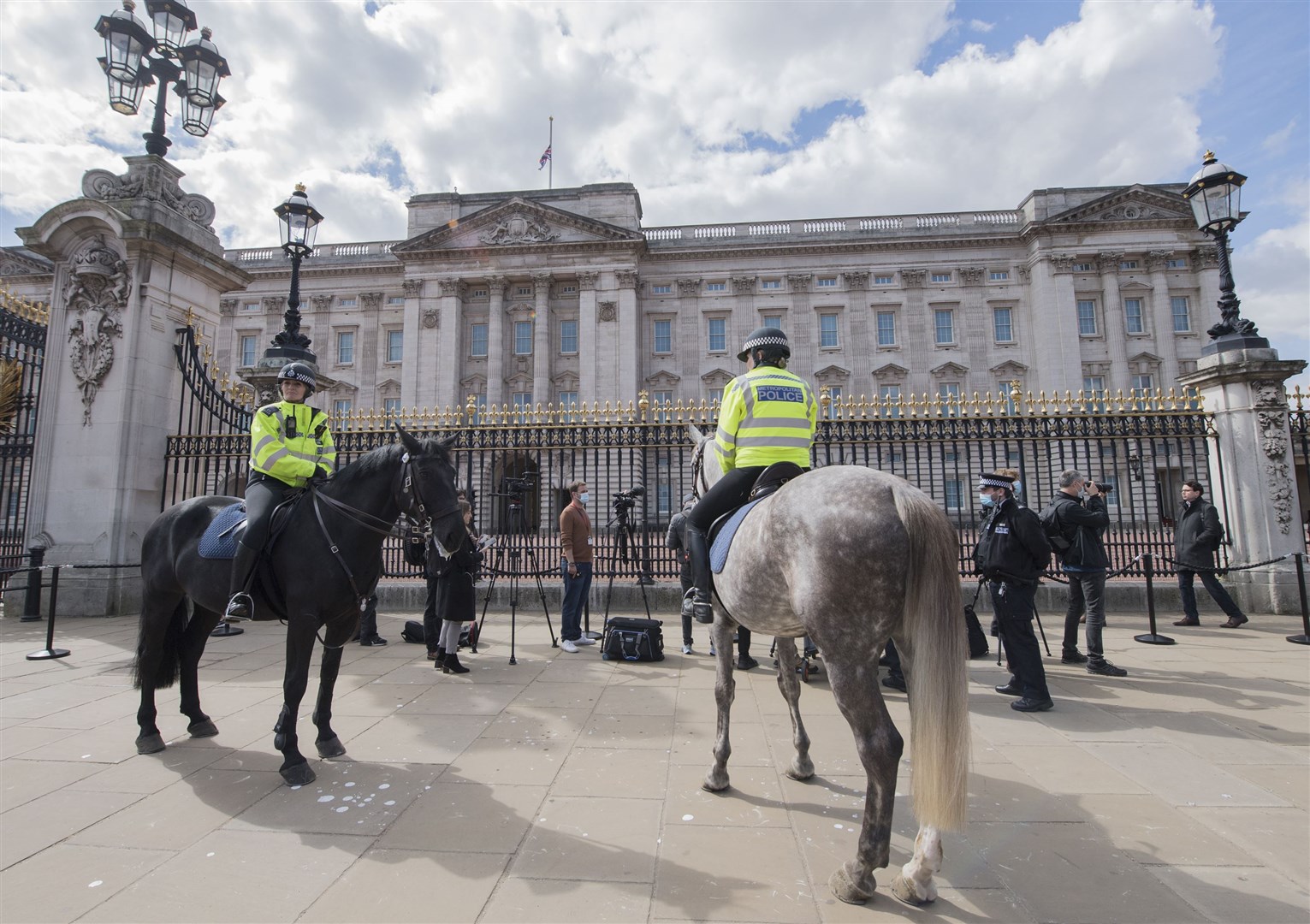 Metropolitan Police officers on horseback observe as members of the media gather outside Buckingham Palace (Ian West/PA)