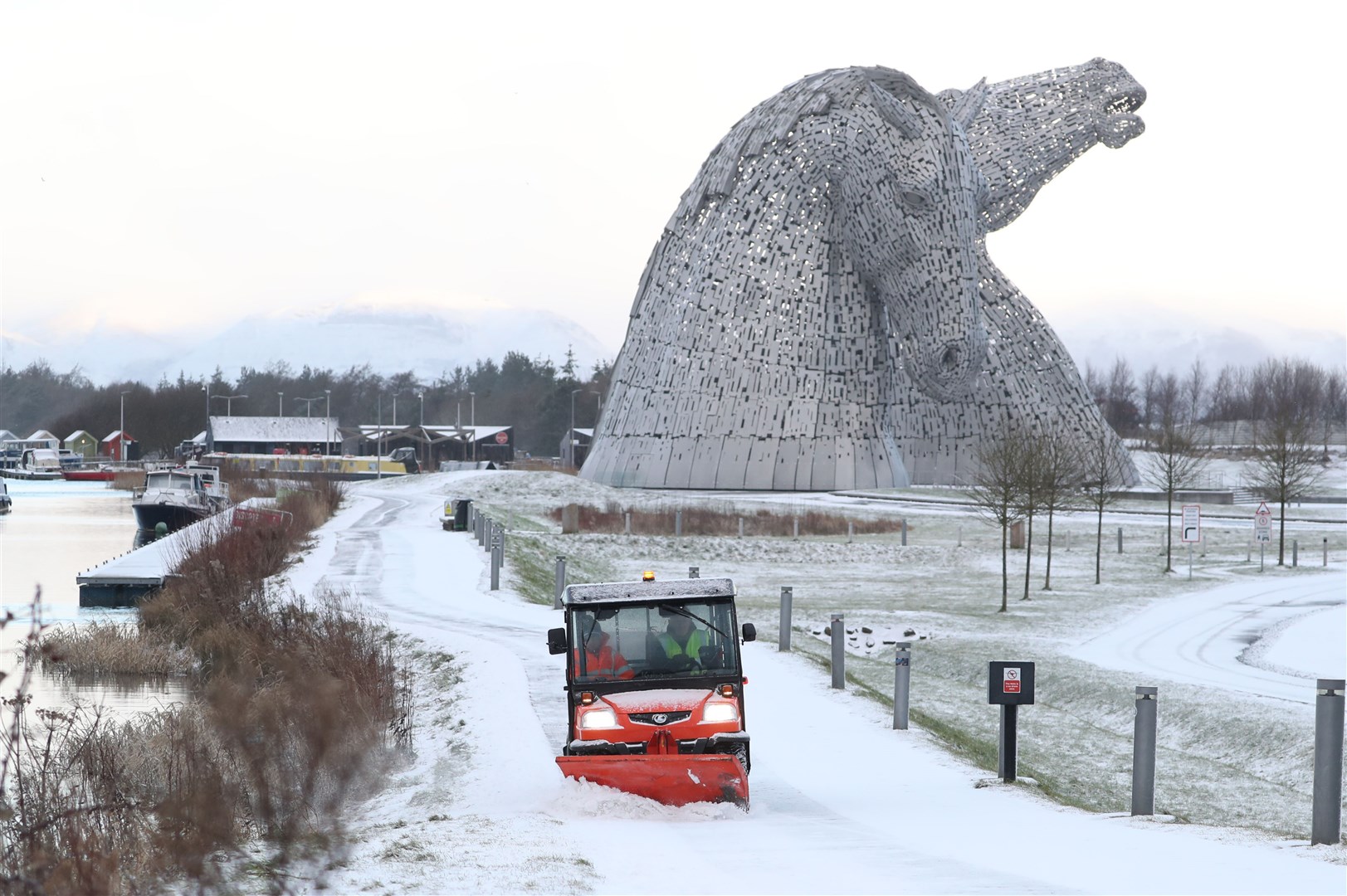 A staff member uses a vehicle to clear snow on a pathway at the Kelpies, near Falkirk in Scotland (Andrew Milligan/PA)