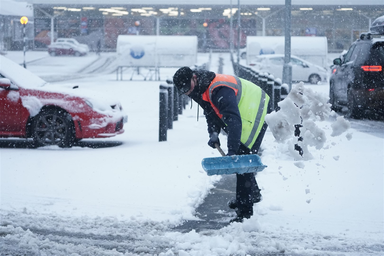 A member of staff from Tesco shovels snow outside the store in Hexham, Northumberland (Owen Humphreys/PA)