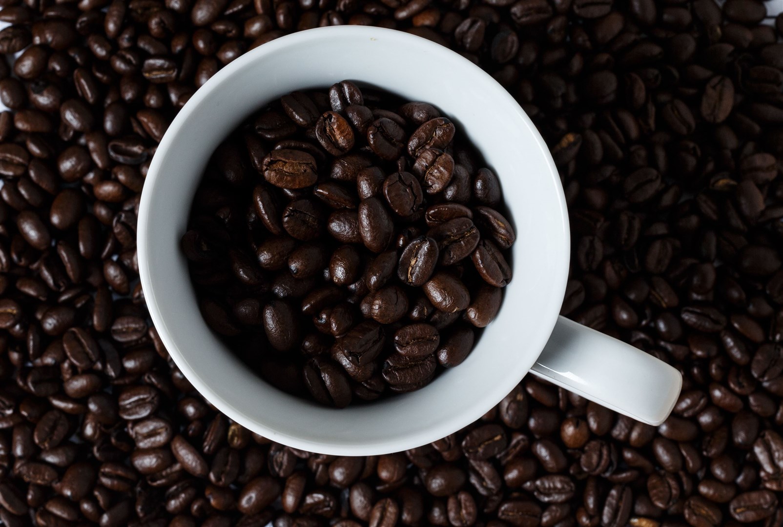 Coffee beans in a mug (John Walton/PA)