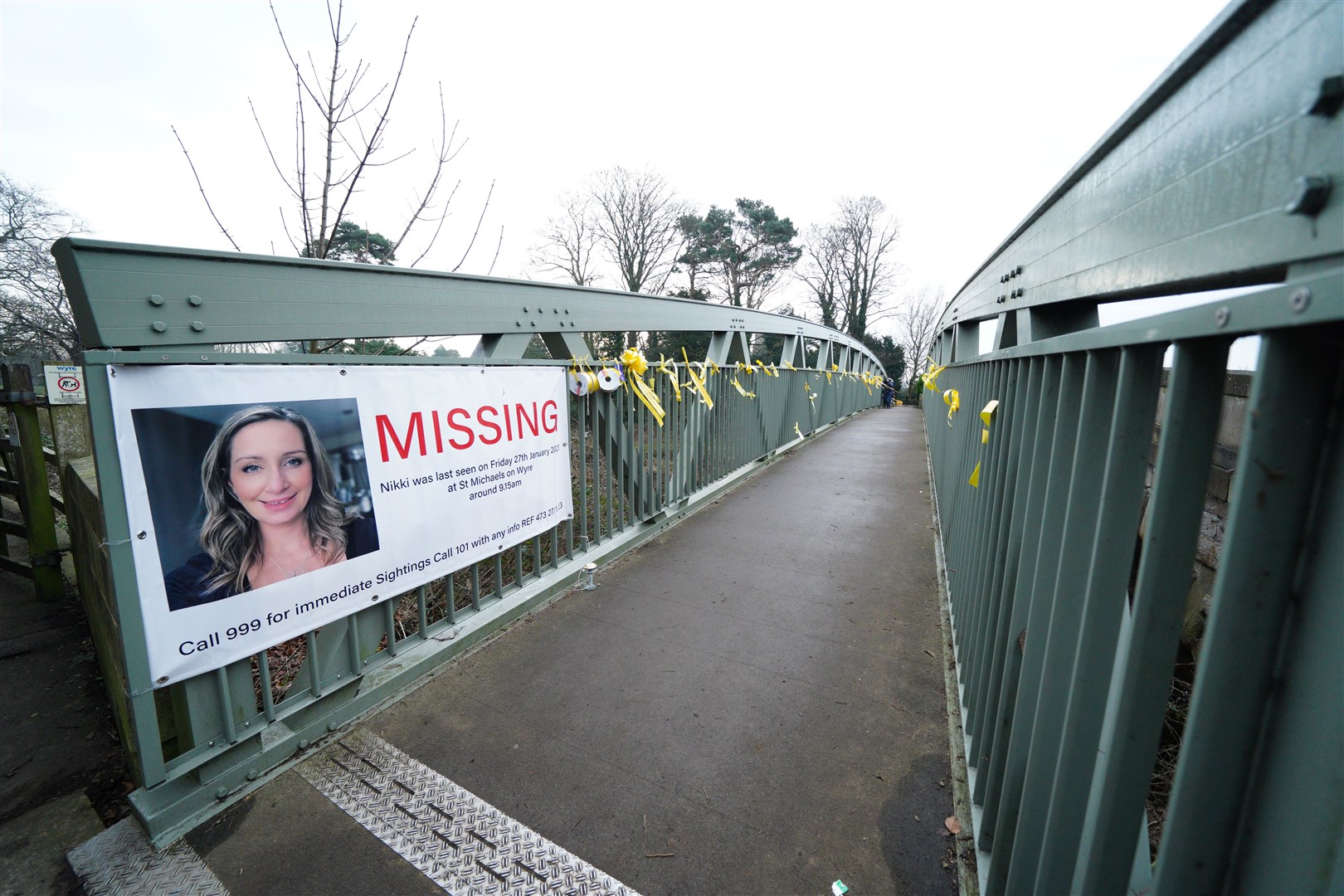A missing person appeal poster for Nicola Bulley and yellow ribbons with messages of hope written on them tied to a bridge over the River Wyre (Peter Byrne/PA)