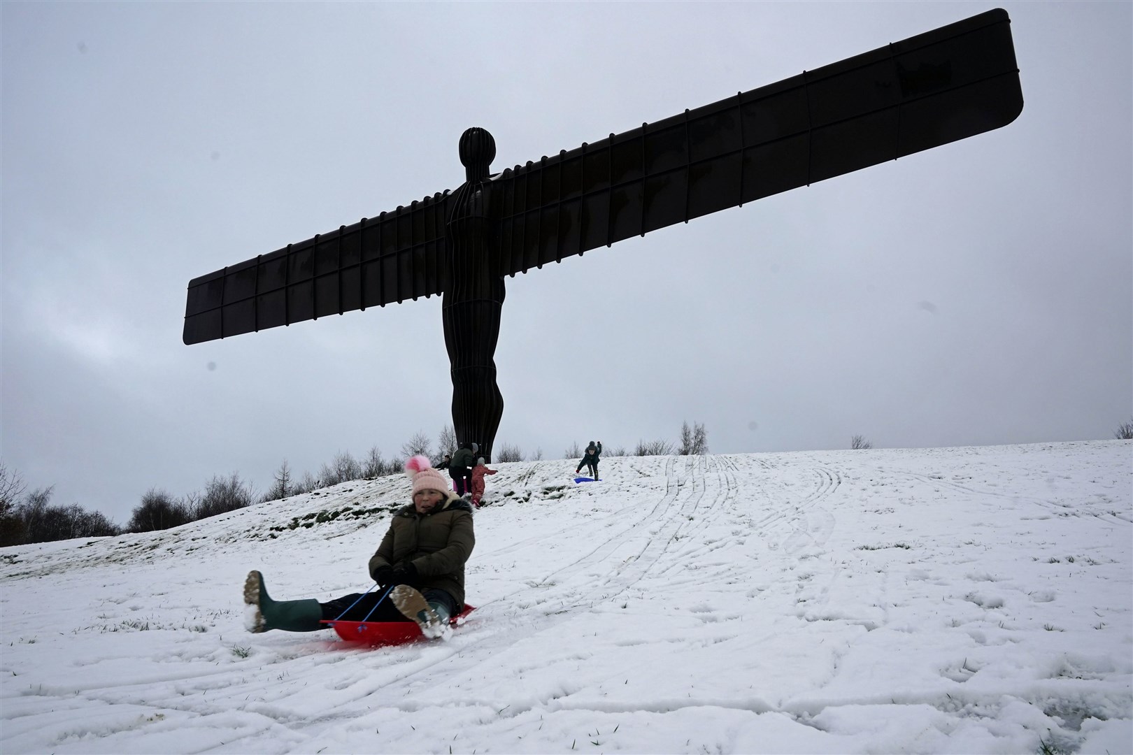 Sledgers have fun in the snow surrounding the Angel of the North near Gateshead, Tyne and Wear (Owen Humphreys/PA)