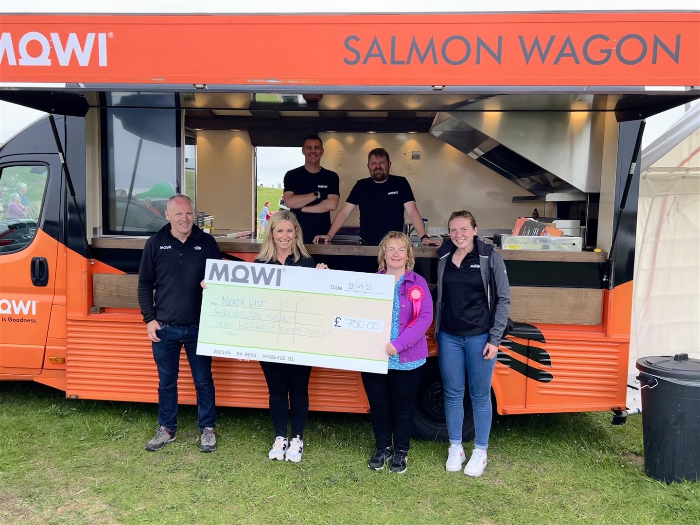 One of the recent beneficiaries of the salmon wagon scheme, Joan Ferguson of North uist Agricultural Society, accepts a cheque from Jayne Mackay, community engagement officer at Mowi Scotland.