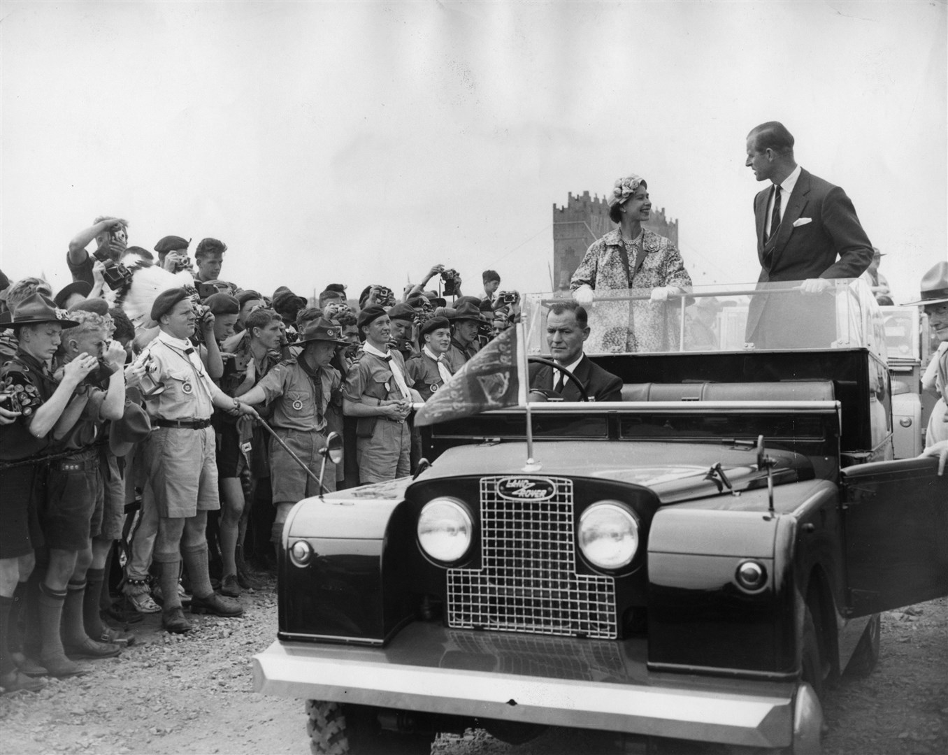 The Queen and the Duke of Edinburgh drive in an open Land Rover through the World Scout Jubilee Jamboree camp in Sutton Park (PA)